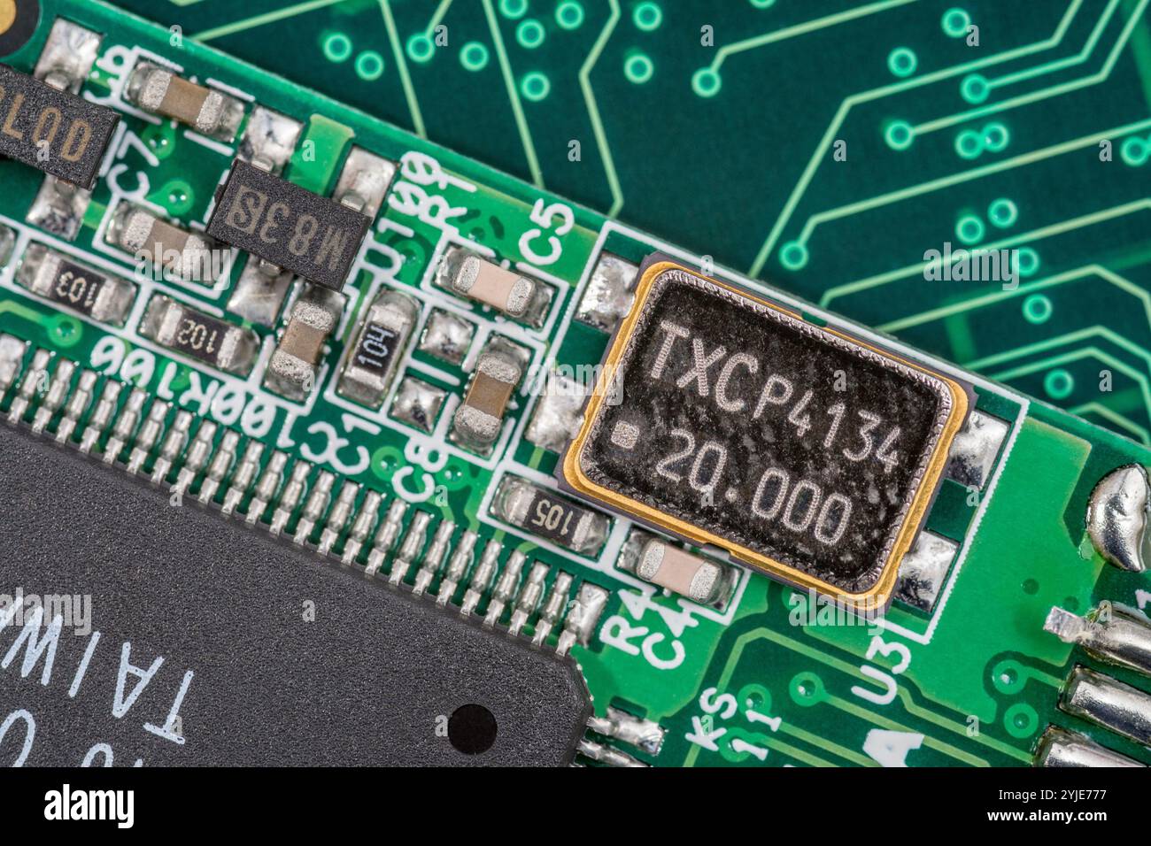 Macro gros plan de SM / oscillateur à quartz métallique à montage en surface sur une carte de circuit imprimé. Évalué à 20Mz avec TXC P4134 gravé dans le métal (? fabricant de pièces) Banque D'Images