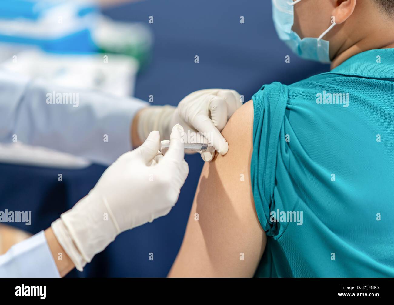 Infirmière tenant une seringue de vaccination injectable chez un patient porteur d'un masque à l'épaule en milieu hospitalier Banque D'Images