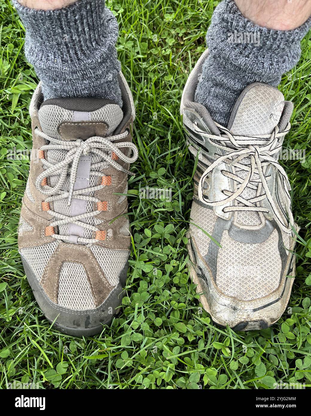 Vous passez une mauvaise journée ? Image des pieds d'un homme avec des chaussettes grises et portant deux chaussures décontractées différentes à l'extérieur sur l'herbe - une chaussure brune et une chaussure grise Banque D'Images