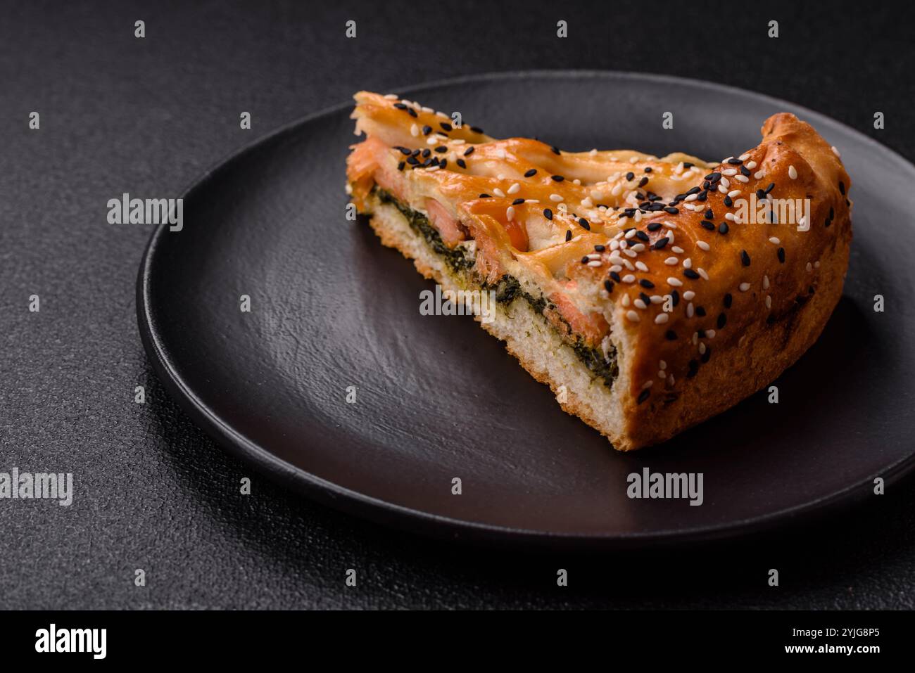 Morceaux de quiche avec saumon, épinards ou brocoli, sel et épices sur fond de béton foncé Banque D'Images