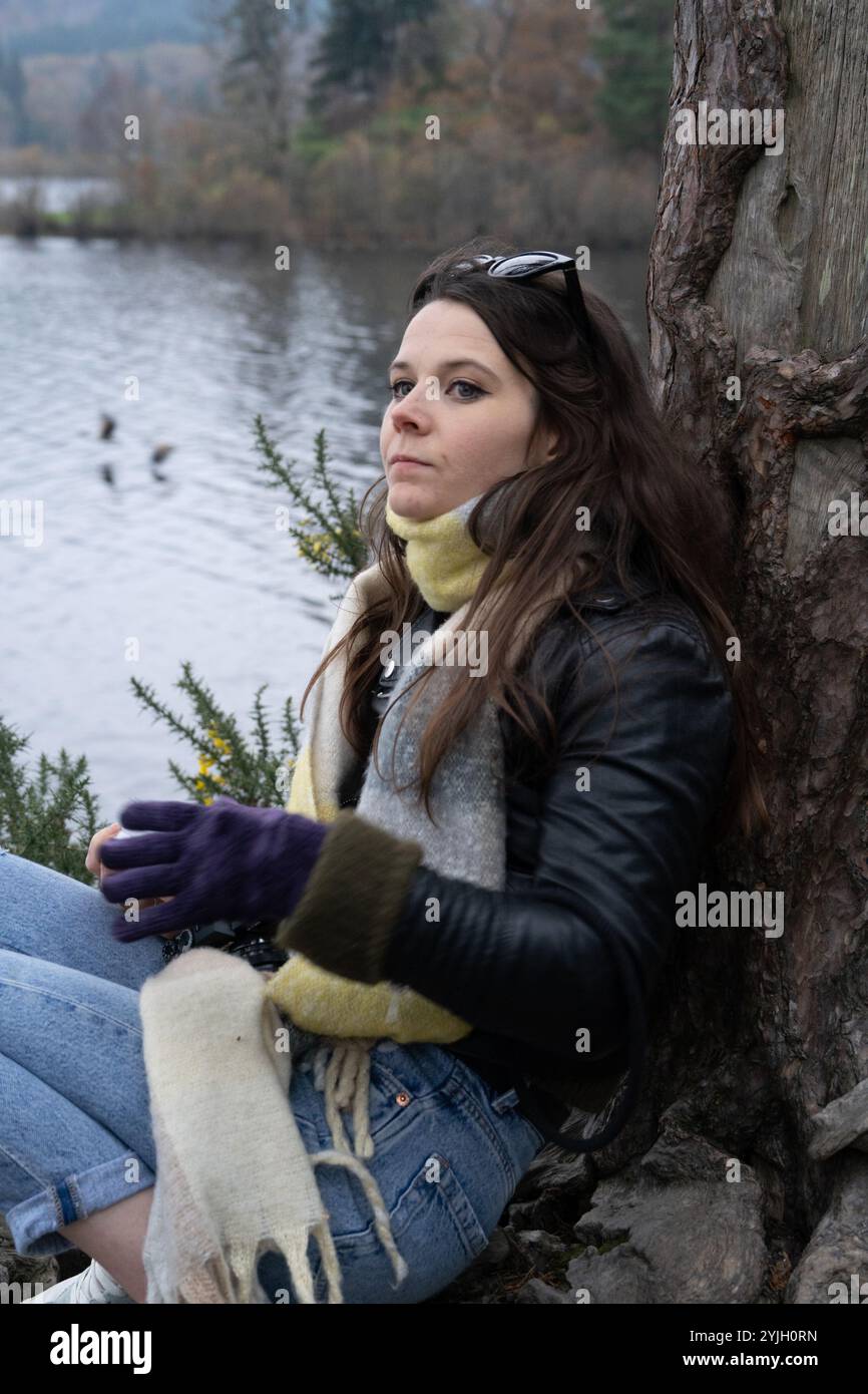Jeune femme se relaxant par le lac avec du thé dans le paysage d'automne de Lake District Banque D'Images