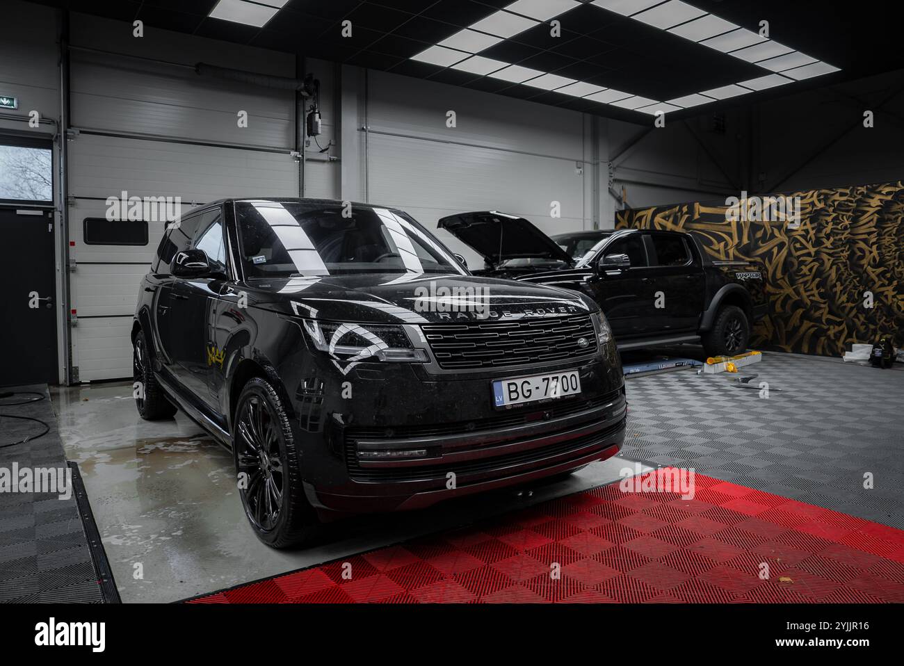 Range Rover noir garé dans un garage moderne avec plancher damier Banque D'Images