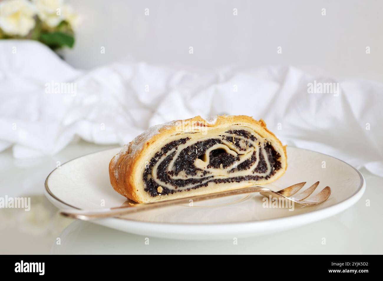 Une tranche de rouleau de graines de pavot sur une assiette blanche. Gâteau savoureux. Banque D'Images