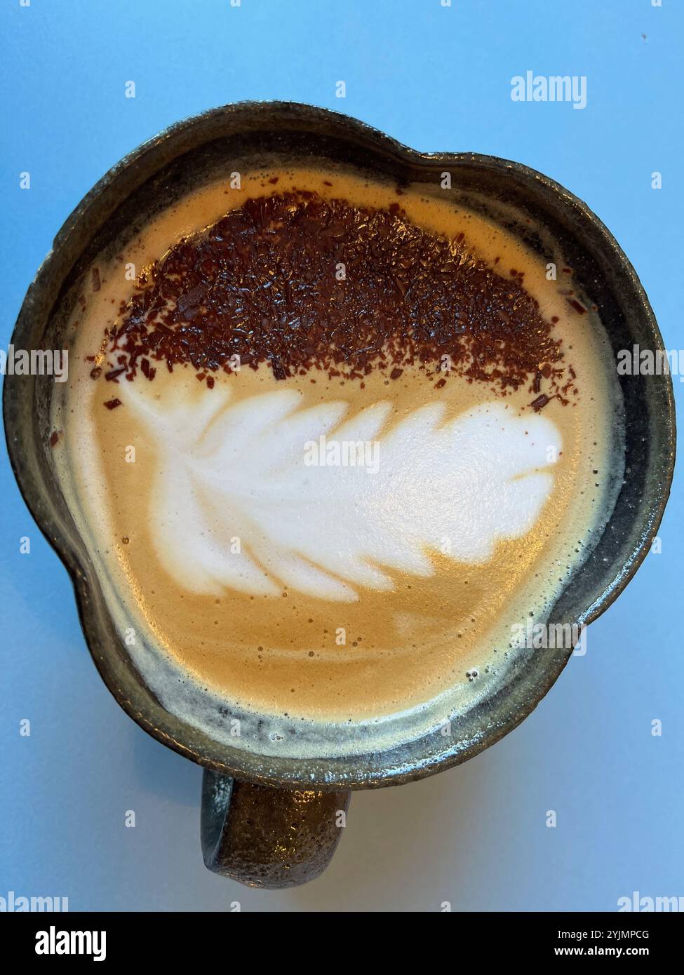 Café cappuccino dans une tasse décorative sur fond bleu - Image de stock capturée avec un smartphone
