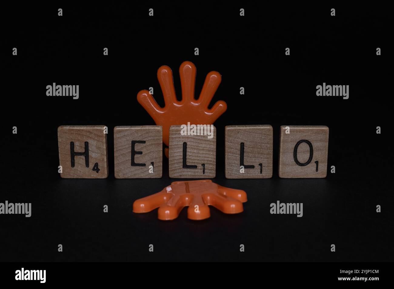 Carreaux de lettres en bois Scrabble avec HELLO Word et deux mains en plastique orange, journée mondiale de bonjour Banque D'Images