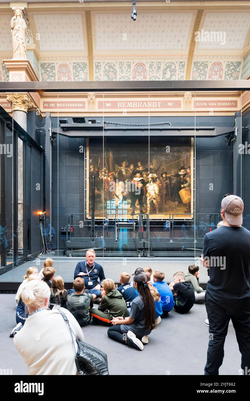 Un groupe d'écoliers devant la veille de nuit de Rembrandt dans le Rijksmuseum. La peinture est étudiée avant les travaux de conservation. Banque D'Images