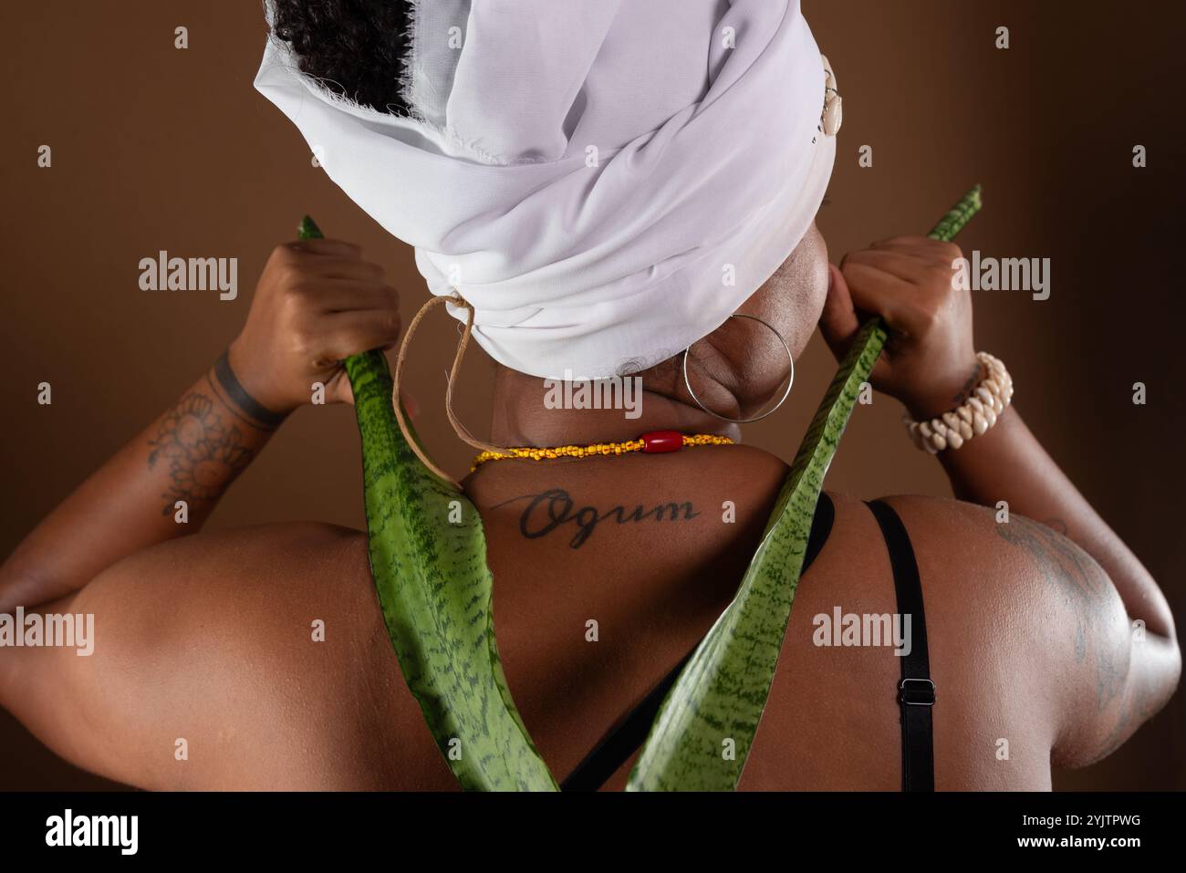 Salvador, Bahia, Brésil - 21 octobre 2024 : femme en vêtements traditionnels Candomblé, montrant un tatouage avec le mot Ogum sur son dos. Salvador, Bahia. Banque D'Images