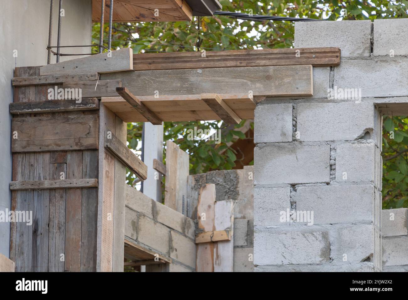 Un gros plan de la construction de poutres en bois sur le dessus d'un mur de blocs de cendre, en cours de construction dans la cour avant. Banque D'Images