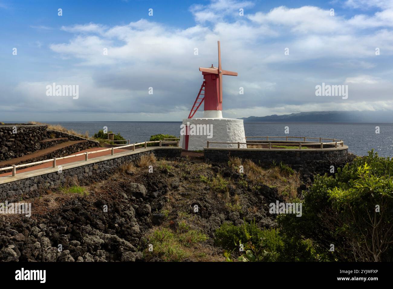 Le moulin à vent d'Urzelina, île de Sao Jorge, Açores, est situé à côté du petit port avec zone de baignade. Banque D'Images