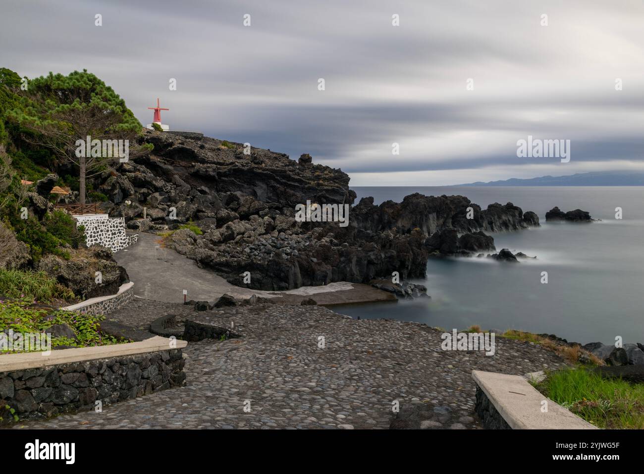 Le moulin à vent d'Urzelina, île de Sao Jorge, Açores, est situé à côté du petit port avec zone de baignade. Banque D'Images