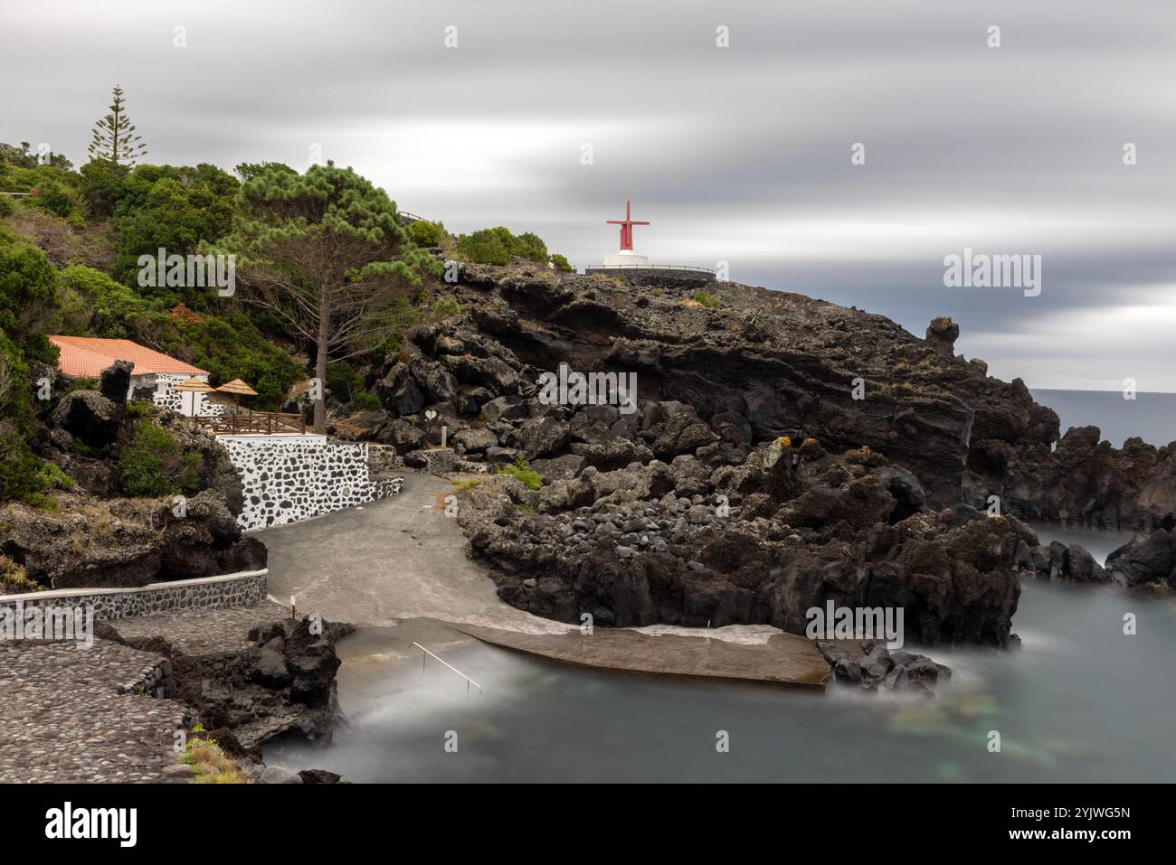 Le moulin à vent d'Urzelina, île de Sao Jorge, Açores, est situé à côté du petit port avec zone de baignade. Banque D'Images