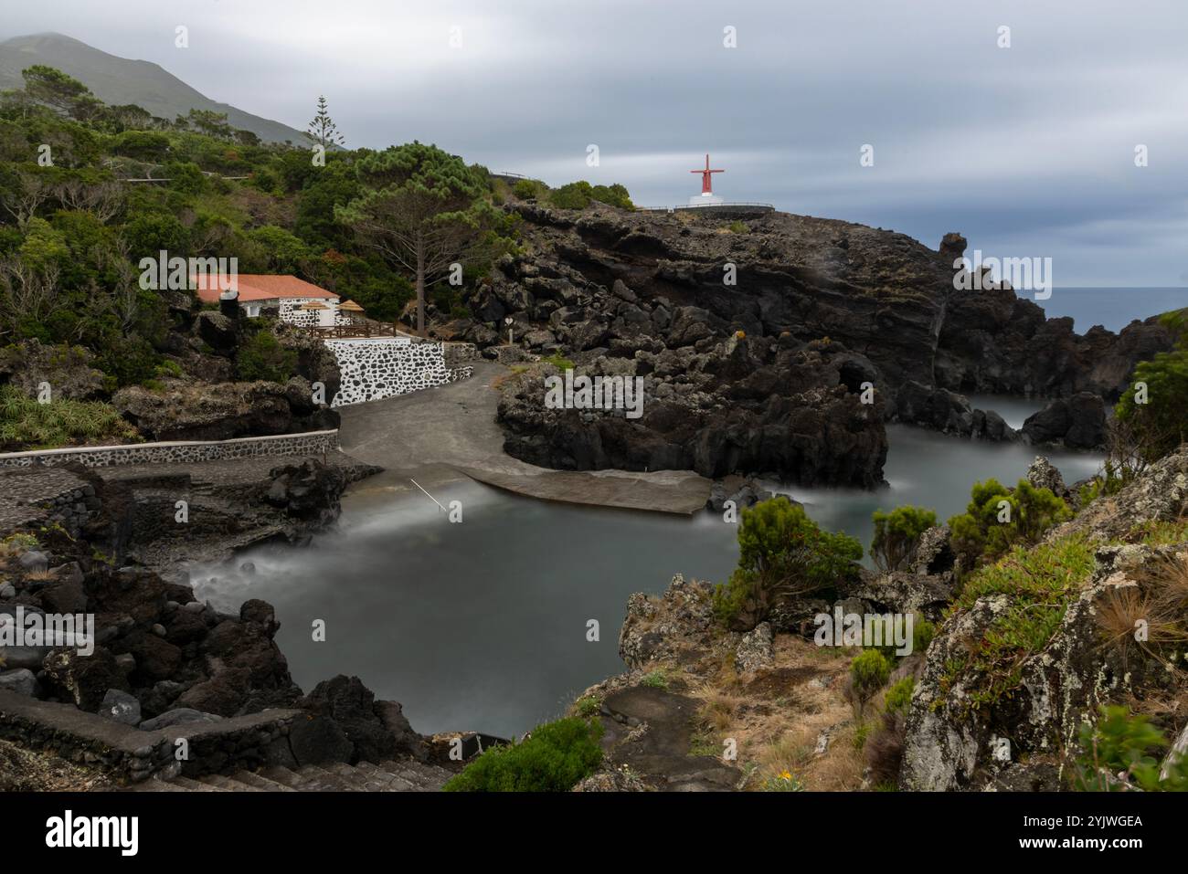 Le moulin à vent d'Urzelina, île de Sao Jorge, Açores, est situé à côté du petit port avec zone de baignade. Banque D'Images