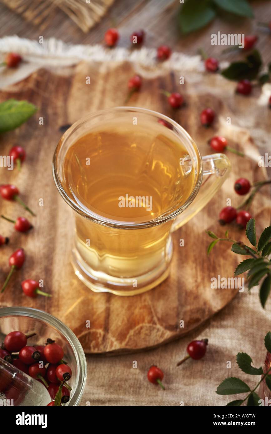 Une tasse de thé à la hanche rose sur une table avec des baies fraîches Banque D'Images
