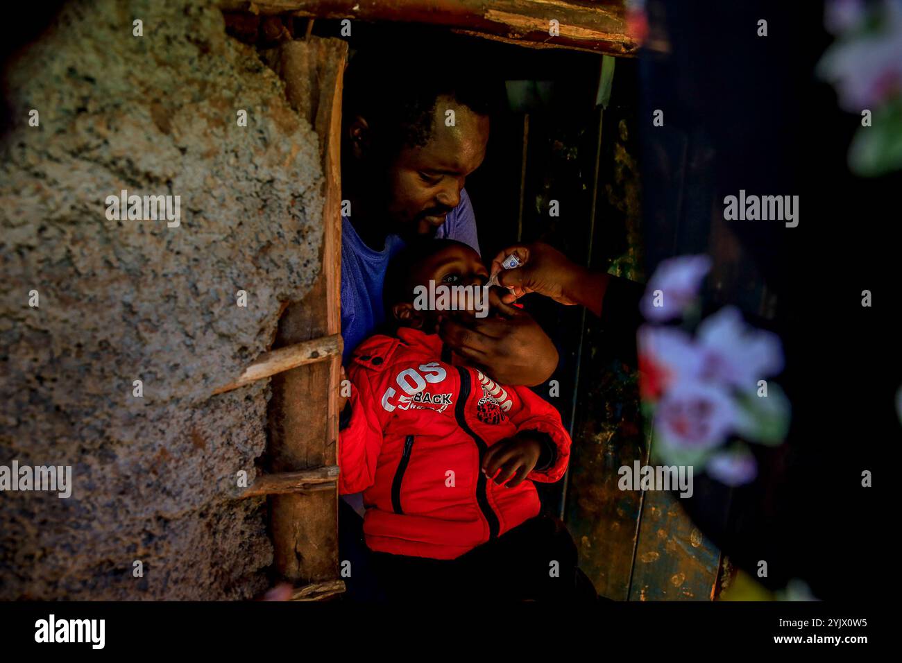 Un père vu porter son bébé pendant une vaccination contre la polio. La polio est un virus qui peut causer la paralysie et qui est facilement évitable grâce au vaccin contre la polio. Le virus se transmet facilement par voie fécale-orale, eau contaminée, aliments ou contact corporel avec une personne infectée, y compris des gouttelettes respiratoires qui pourraient mener à une paralysie mortelle si aucun diagnostic médical rapide n'est pris. Il affecte principalement les enfants de moins de 5 ans, mais aussi toute personne d'un âge différent, qui n'est pas vaccinée peut contacter les maladies. L'Association pédiatrique du Kenya (KPA), une organisation professionnelle à but non lucratif comprenant p Banque D'Images