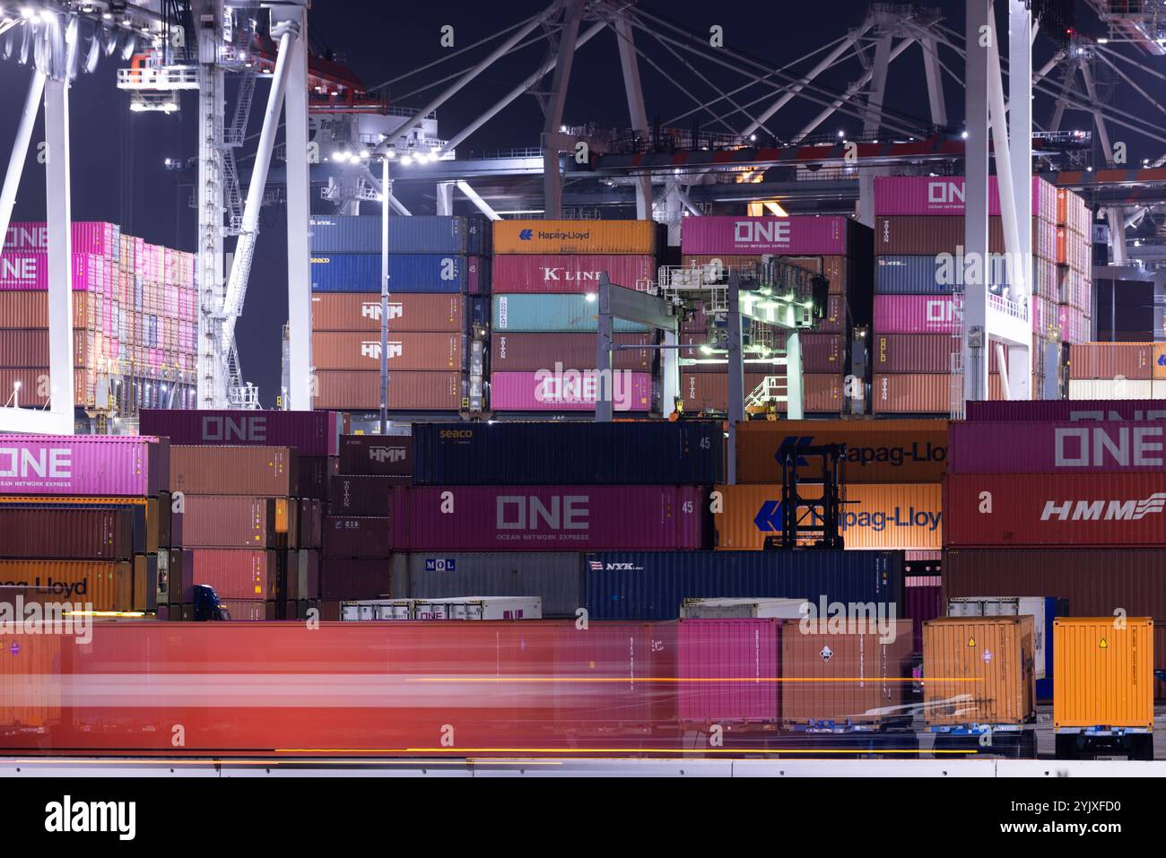 Wilmington, Californie, États-Unis - 16 juillet 2021 : des grues déchargent des conteneurs intermodaux d'un navire au port de Los Angeles, tandis que des semi-camions transportent t Banque D'Images