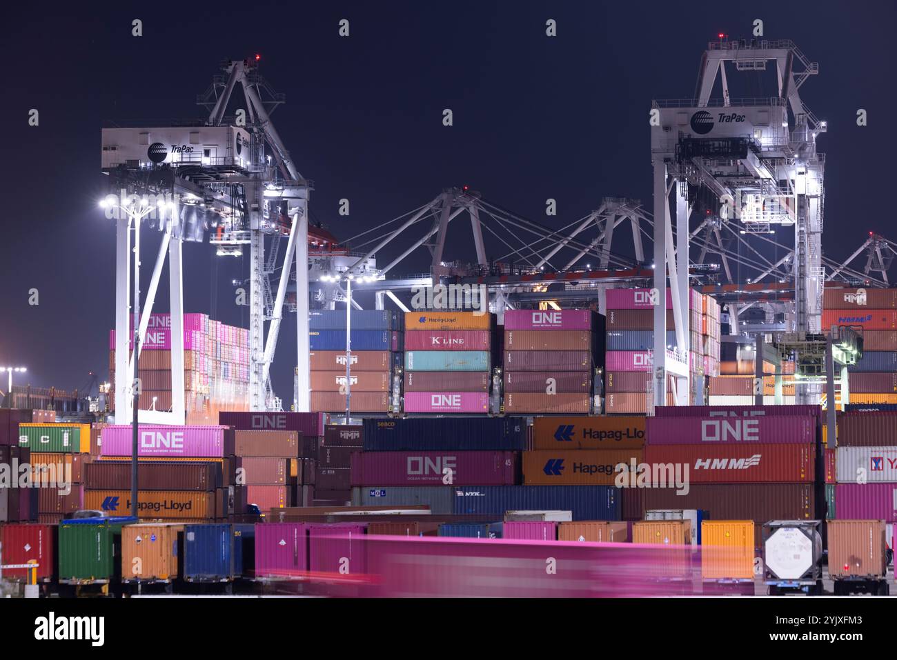 Wilmington, Californie, États-Unis - 16 juillet 2021 : des grues déchargent des conteneurs intermodaux d'un navire au port de Los Angeles, tandis que des semi-camions transportent t Banque D'Images