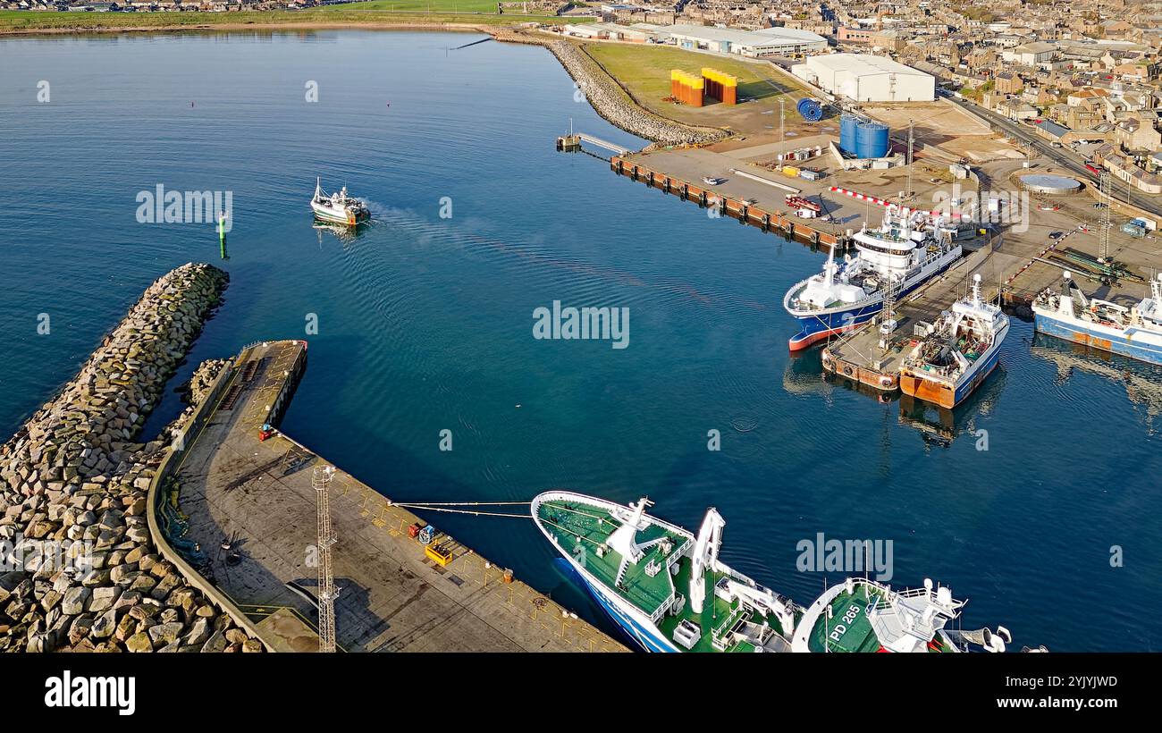 Peterhead Aberdeenshire Écosse le port de grands navires de pêche amarrés et un chalutier passant Merchants Quay vers la haute mer Banque D'Images