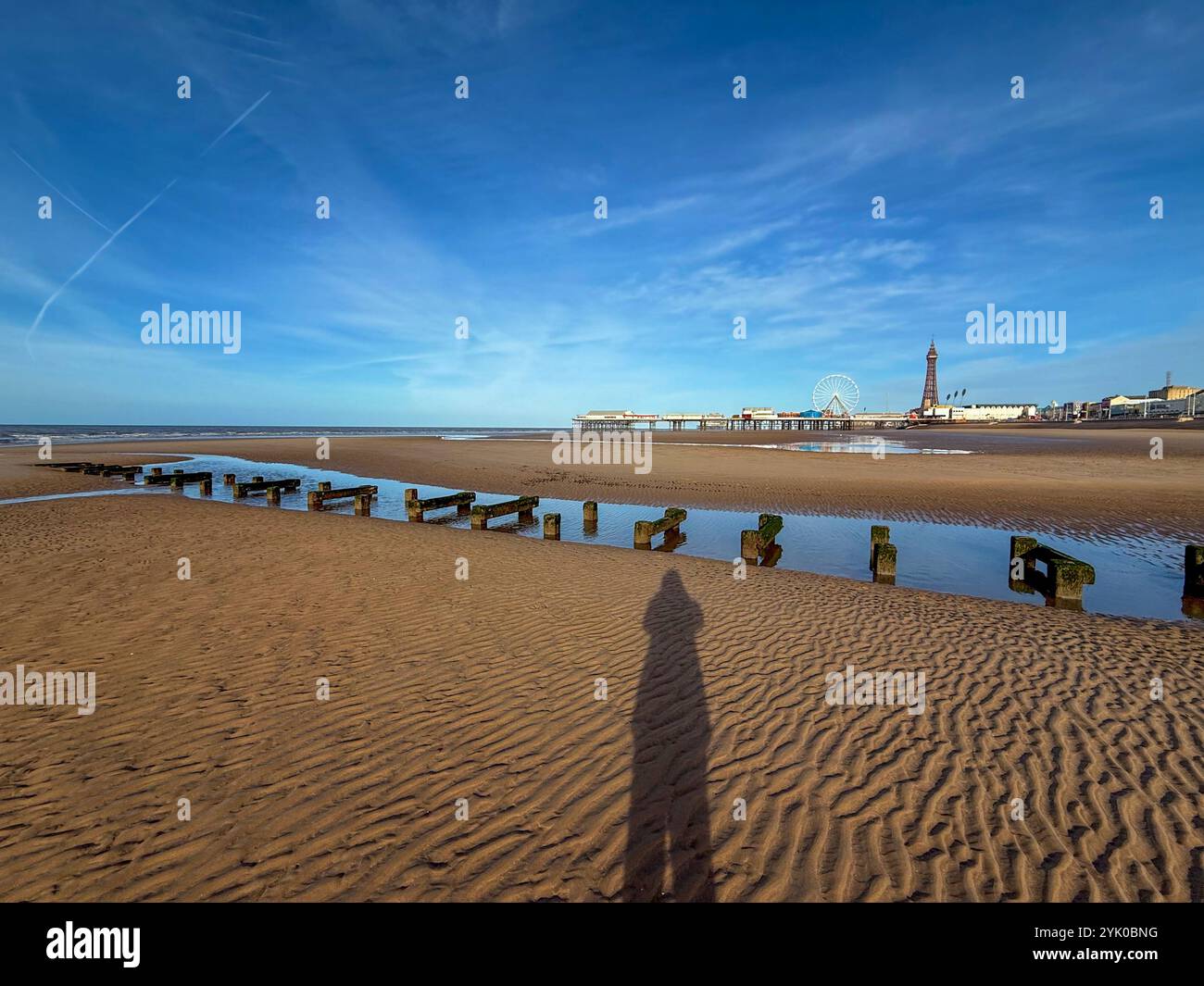 Ombre de figure sur la plage de Blackpool à marée basse avec Central Pier et Blackpool Tower à distance Banque D'Images