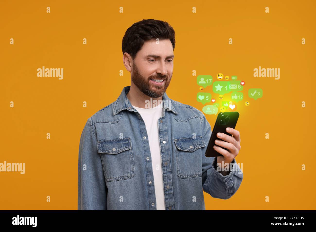 Homme heureux utilisant le téléphone portable sur fond orange. Nouveau signe de message et autres notifications sur gadget Banque D'Images