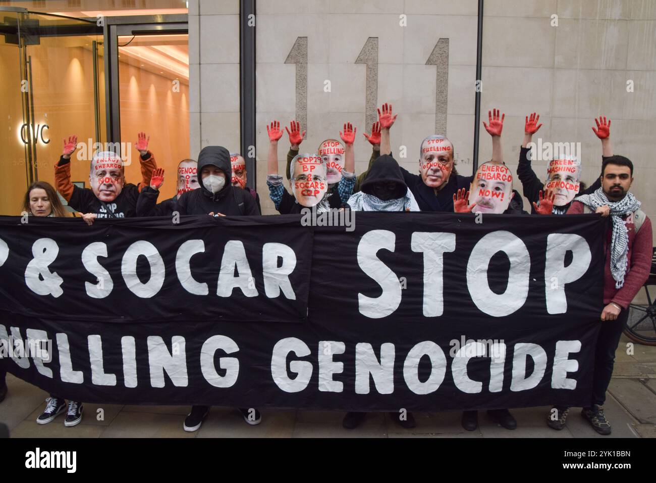 Londres, Royaume-Uni. 16 novembre 2024. Des manifestants portant des masques du président turc Recep Erdogan et d'autres se tiennent les mains couvertes de faux sang à côté d'une banderole exigeant la fin du génocide devant les bureaux de la société SOCAR on the Strand pendant la manifestation. Les manifestants ont défilé dans le centre de Londres pour exiger la justice climatique et la fin des combustibles fossiles, et en solidarité avec la Palestine, alors que la COP29 se poursuit en Azerbaïdjan. Crédit : SOPA images Limited/Alamy Live News Banque D'Images