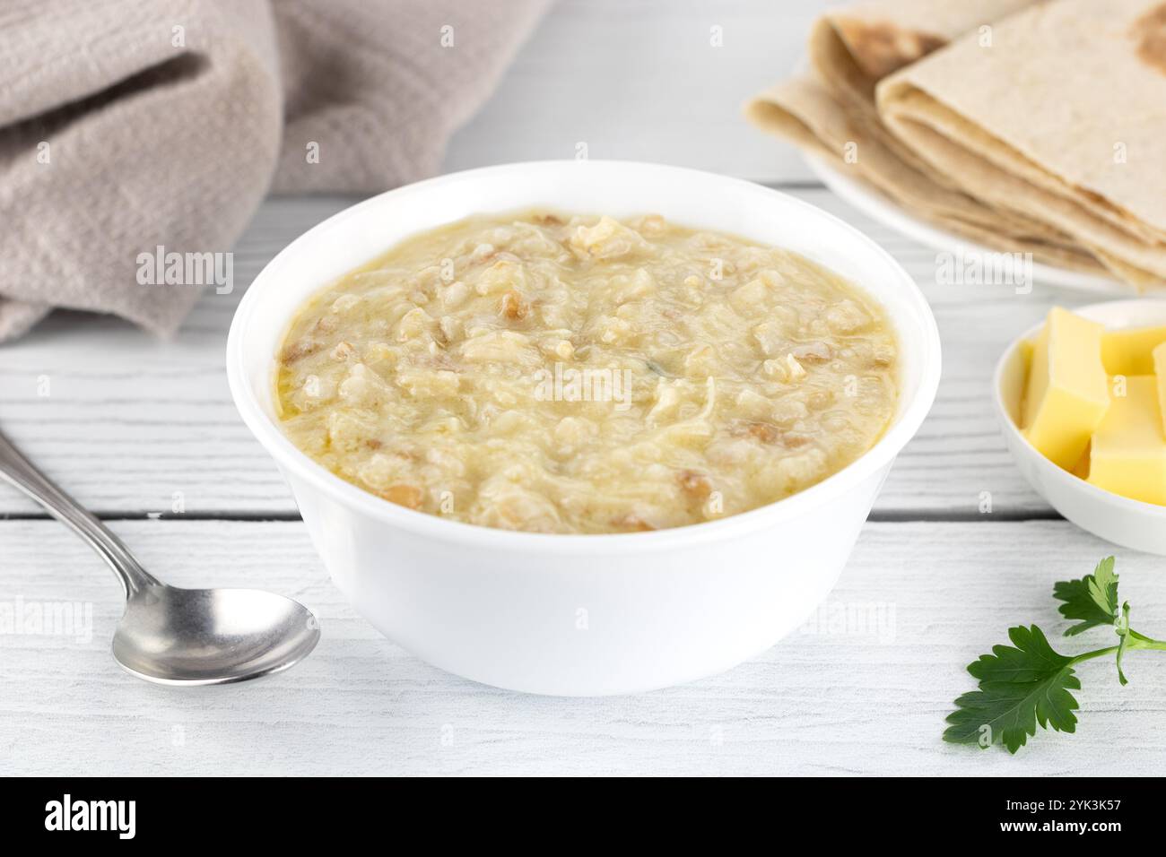 Bouillie arménienne traditionnelle - harissa avec poulet, beurre et pain lavash. Fond en bois blanc. Vue de dessus. Banque D'Images