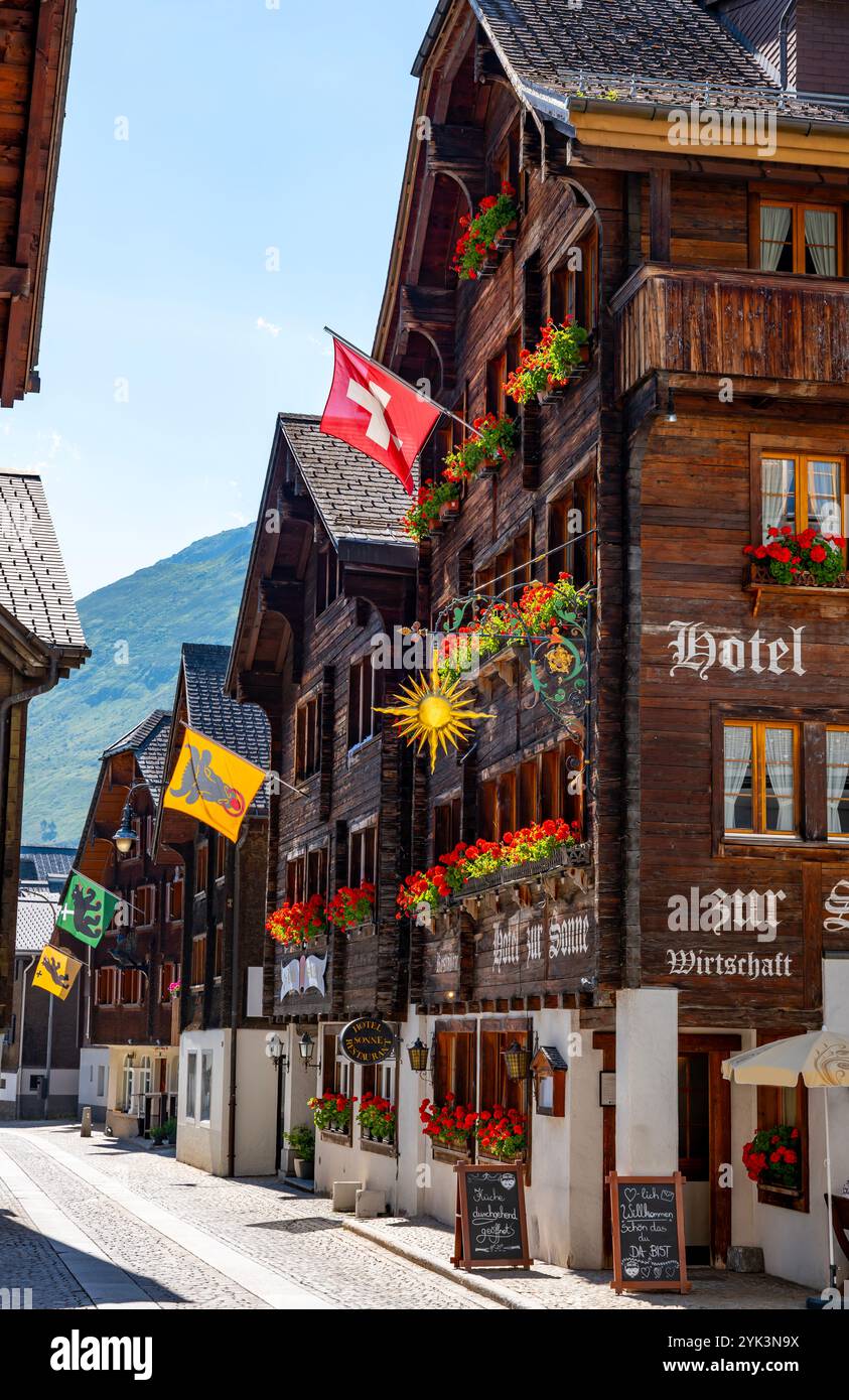 Belle rue de la ville dans la vieille ville avec maisons et hôtel et avec montagne dans une journée d'été ensoleillée à Andermatt, Uri, Suisse. Banque D'Images