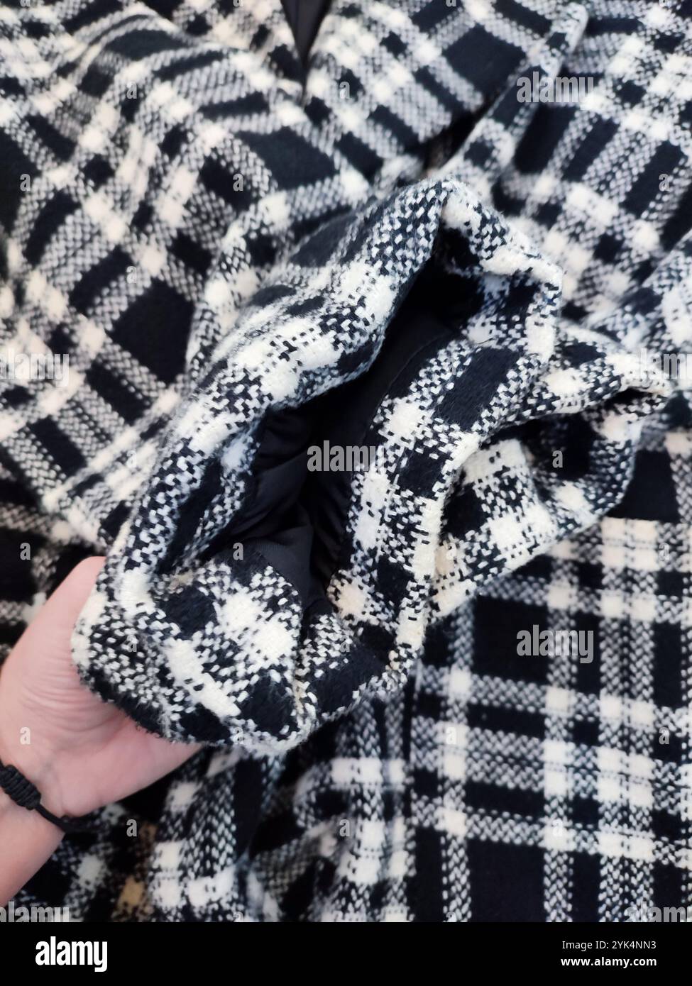 Manteau poignets gros plan, manteau à carreaux noir blanc, tissu, textile, détails de vêtements, pose plate sur fond de marbre blanc Banque D'Images