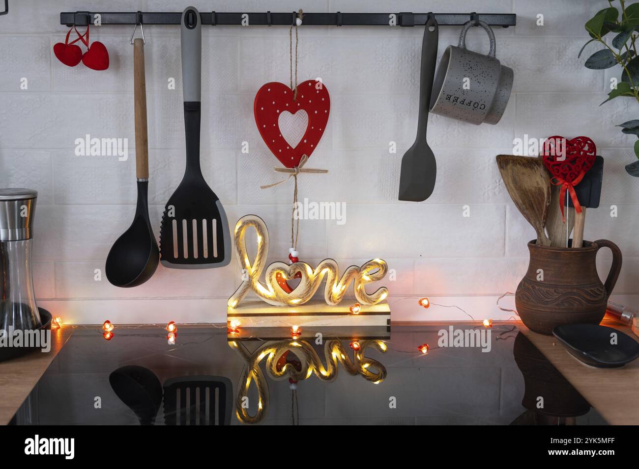 L'intérieur de la cuisine de la maison est décoré de coeurs rouges pour la Saint-Valentin. Décoration sur la table, cuisinière, ustensiles, ambiance festive dans un fari Banque D'Images