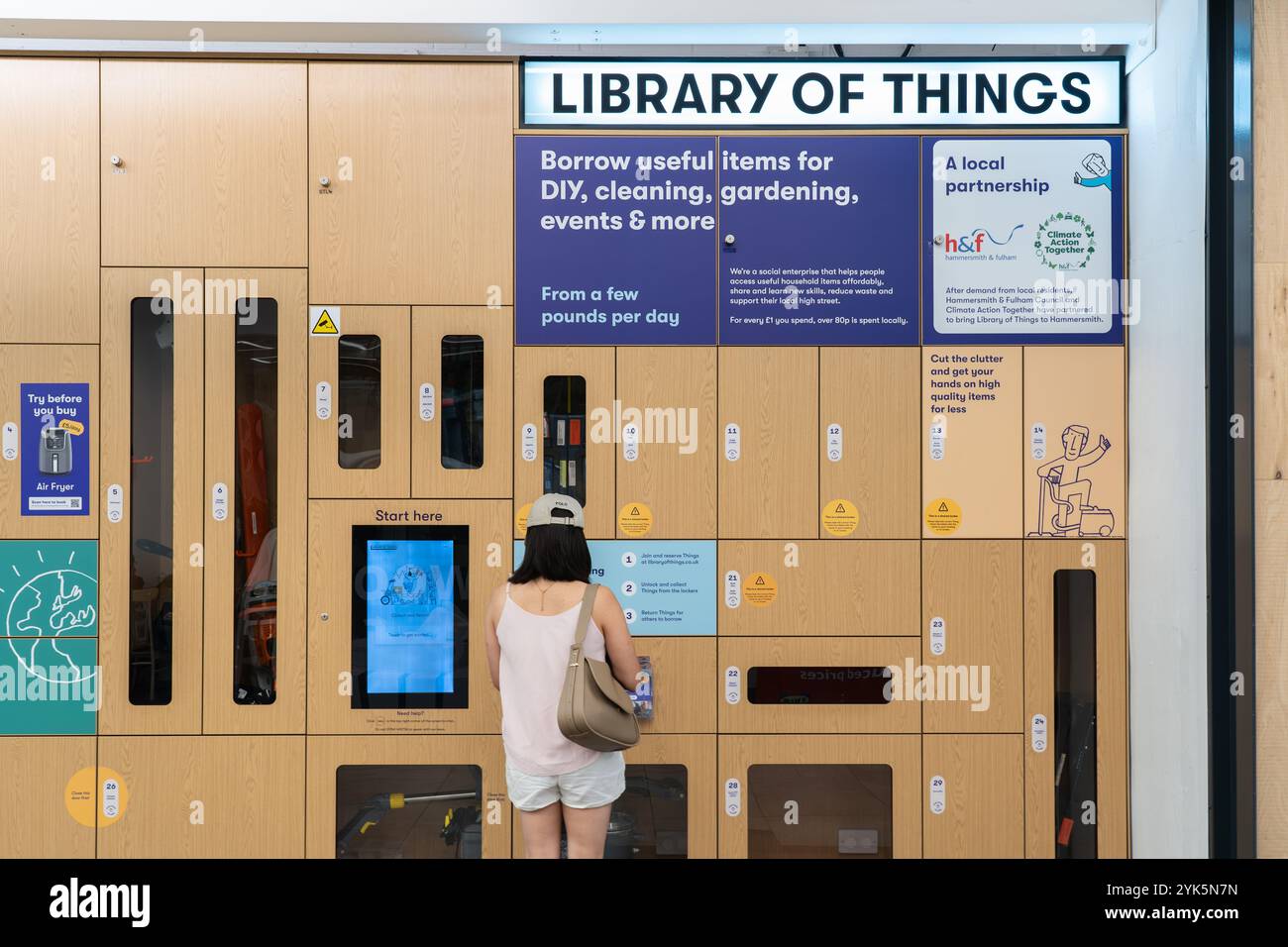 Femme empruntant un objet à la Bibliothèque des objets, un service de location / emprunt d'outils à distance dans le centre commercial Livat Hammersmith, Londres Banque D'Images Femme empruntant un objet à la Bibliothèque des objets, un service de location / emprunt d'outils à distance dans le centre commercial Livat Hammersmith, Londres Banque D'Images