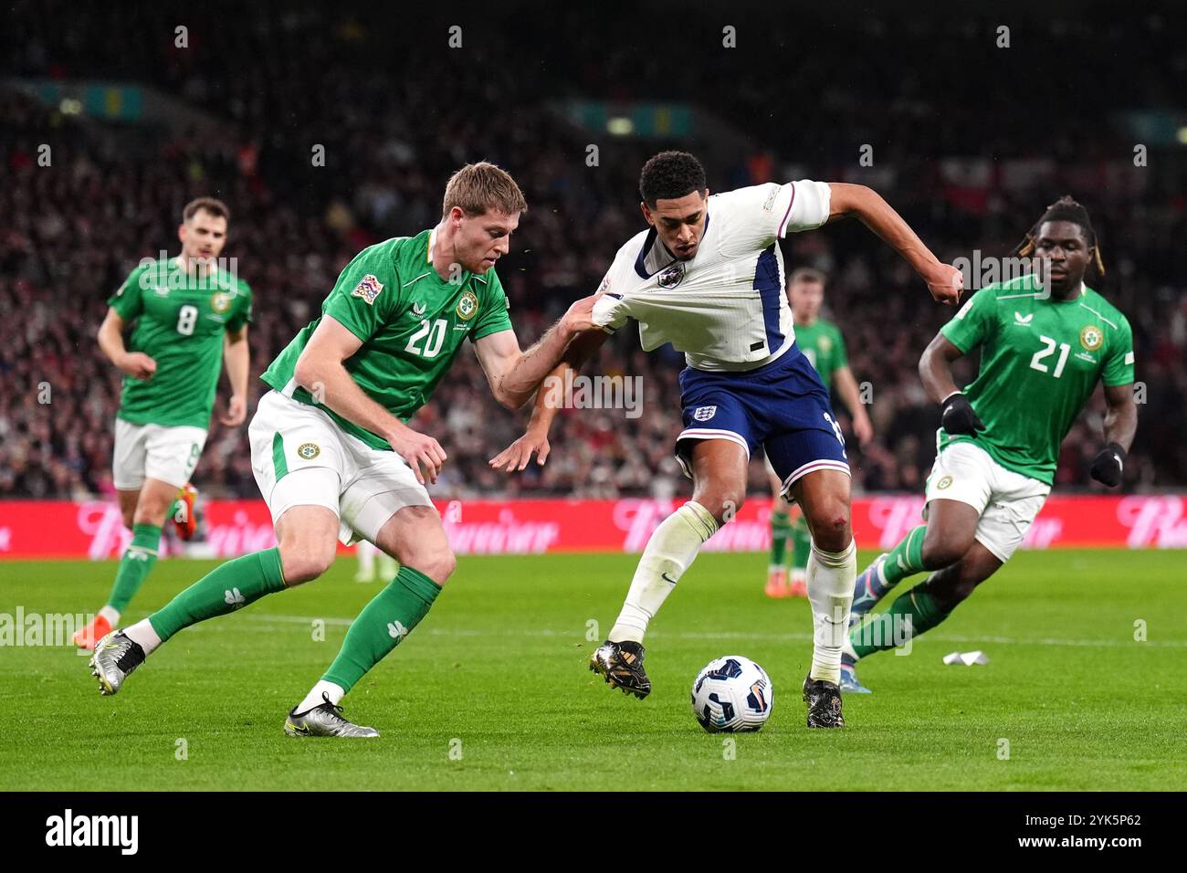 Jude Bellingham (au centre) et Mark McGuinness (en), en Irlande, se battent pour le ballon lors du match du Groupe B2 de l'UEFA Nations League au stade de Wembley, à Londres. Date de la photo : dimanche 17 novembre 2024. Banque D'Images