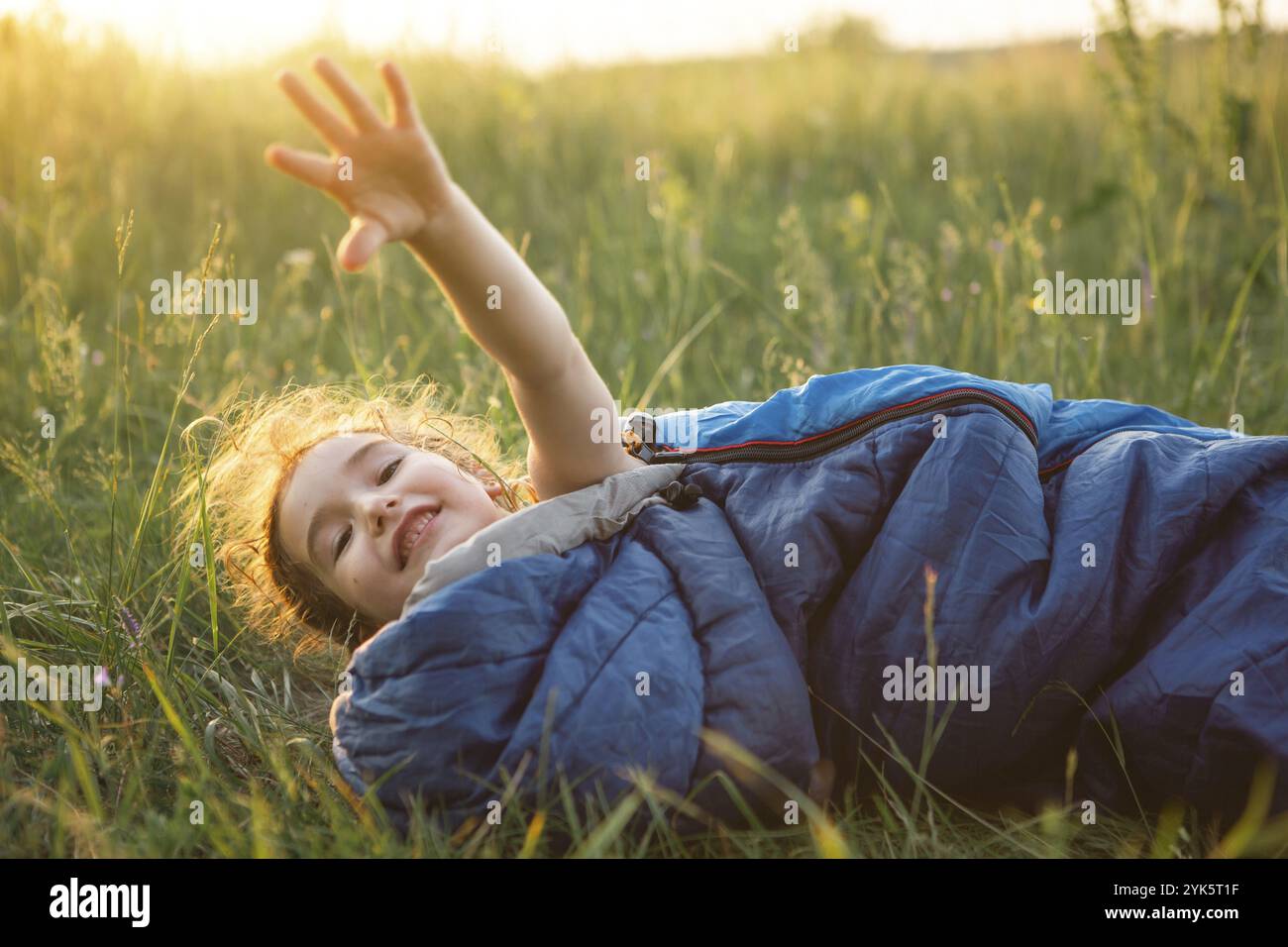 Un enfant dort dans un sac de couchage sur l'herbe dans un voyage de camping, des loisirs de plein air respectueux de l'environnement, un mode de vie sain, l'heure d'été. Doux et paisible s Banque D'Images