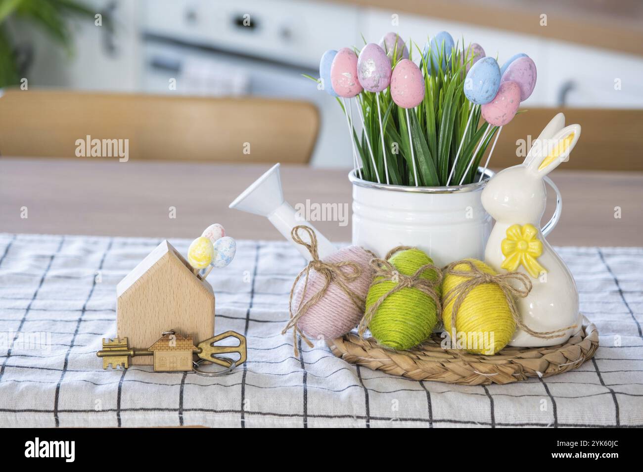 Clé et minuscule maison de maison confortable avec décor de Pâques avec lapin et oeufs sur la table de la cuisine. Bâtiment, conception, projet, déménagement à la nouvelle maison, hypothèque, Banque D'Images