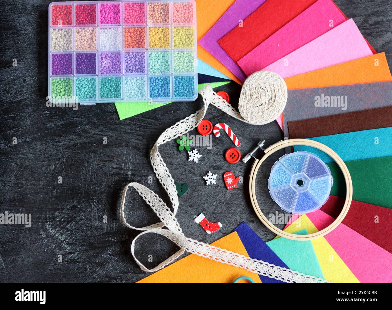 Image colorée des fournitures d'artisanat. Tissu feutre, perles de verre, cerceau de broderie, ciseaux et bande de roulement sur fond sombre. Passe-temps et concept de temps libre. Banque D'Images