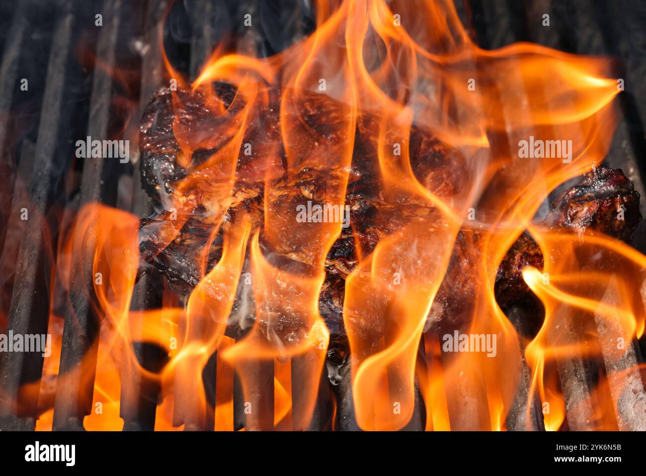 Gros plan sur des steaks de bœuf à la rivée et fumant sur une grille extérieure à feu ouvert avec grille en fonte métallique, vue en grand angle Banque D'Images