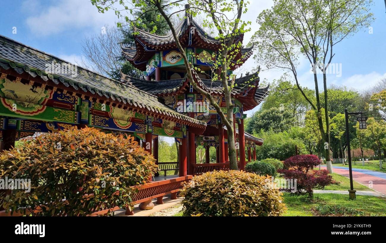 Bâtiment de style pagode avec ses sculptures complexes et sa peinture colorée se distingue sur fond d'arbres verdoyants et d'un ciel bleu clair. Banque D'Images
