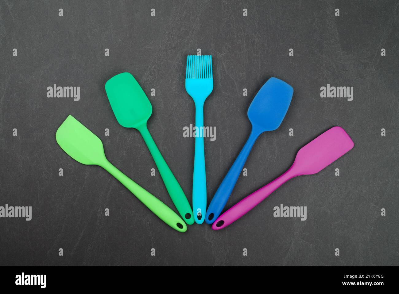 Cinq spatules et brosses de cuisson en silicone sur panneau d'ardoise noire avec espace de copie, ustensiles de cuisine culinaires modernes colorés, gros plan, table élevée t Banque D'Images