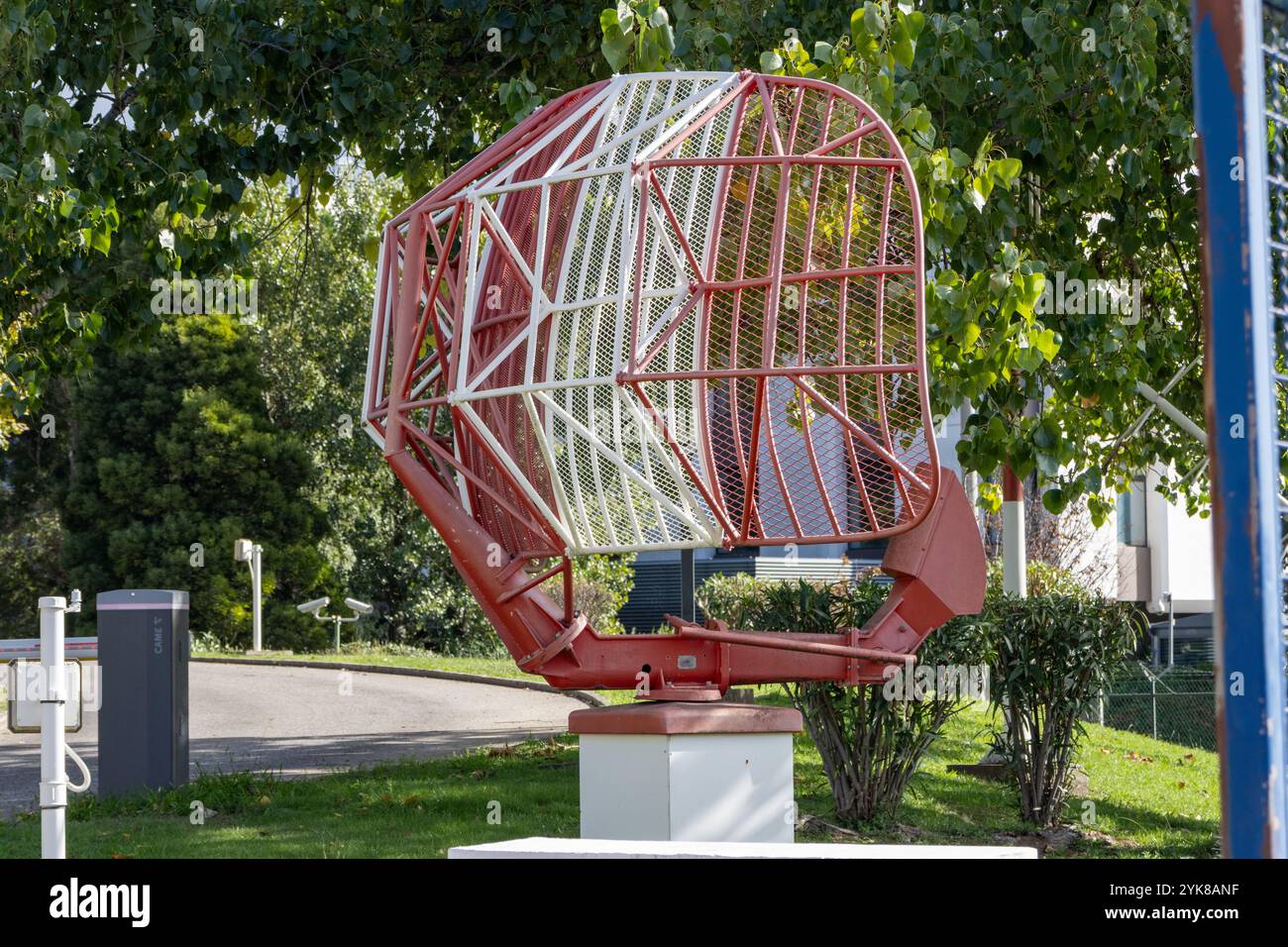 L'antenne radar marine rouge et blanche tourne et cherche sur le champ vert près des arbres Banque D'Images