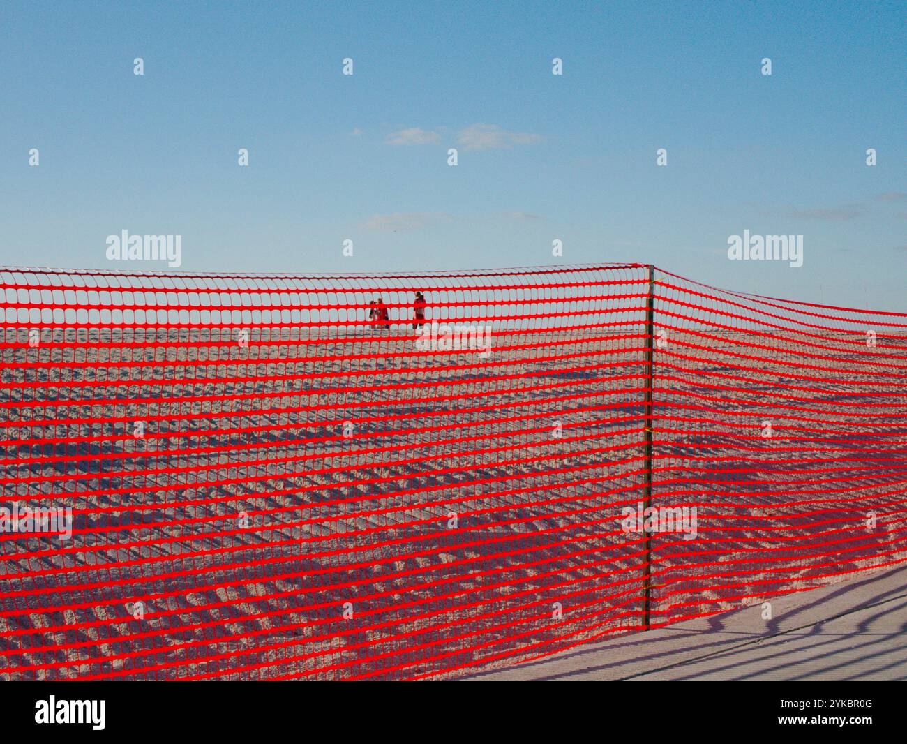 Large vue sur le trottoir à travers la barrière de sécurité orange à 3 personnes sur la plage de sable vers le golfe du Mexique. Traces de pneus dans la restauration de plage de dunes de sable. Banque D'Images