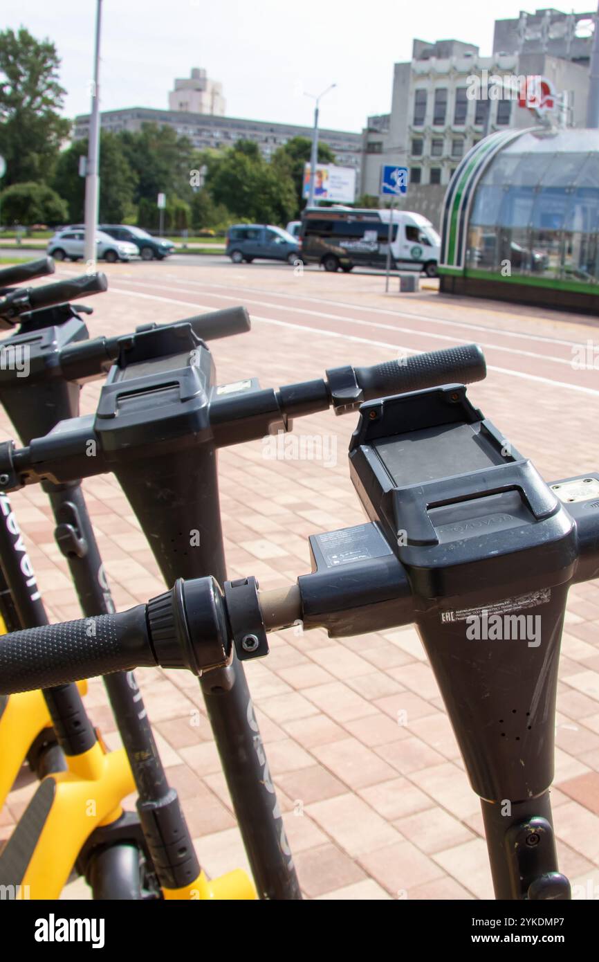 Biélorussie, Minsk - 18 juillet, 2024 : une rangée de scooters jaunes et noirs élégants est soigneusement garée dans un parking spacieux, mettant en valeur t urbain moderne Banque D'Images