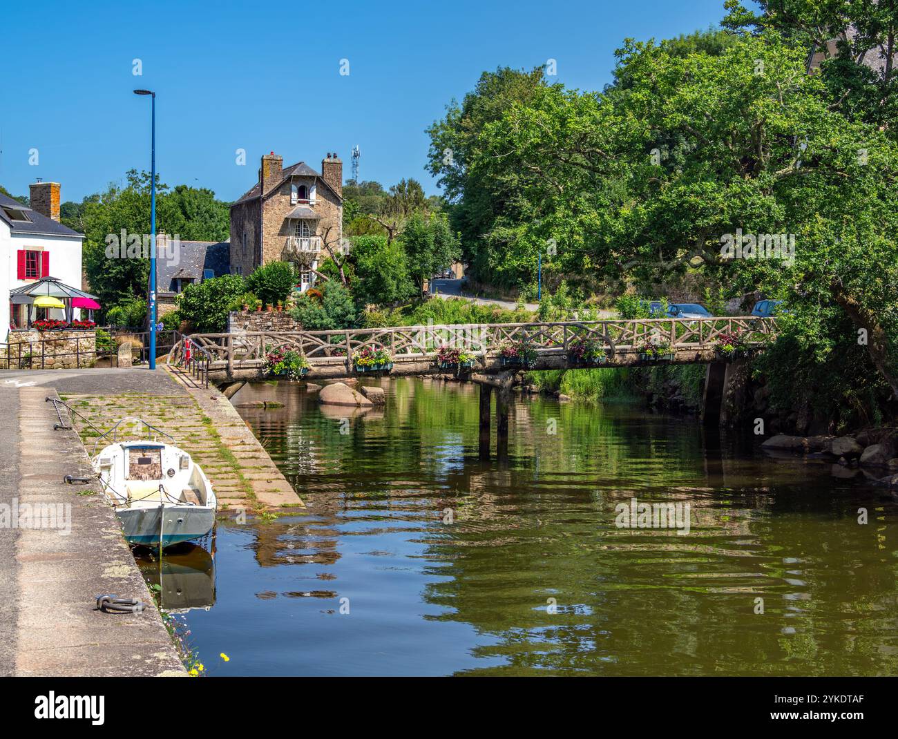 Pont Aven, France - 29 juillet 2024 : une scène pittoresque à Pont Aven avec une rivière Aven avec un petit bateau amarré sur le côté. Un pont en bois, surr Banque D'Images Pont Aven, France - 29 juillet 2024 : une scène pittoresque à Pont Aven avec une rivière Aven avec un petit bateau amarré sur le côté. Un pont en bois, surr Banque D'Images
