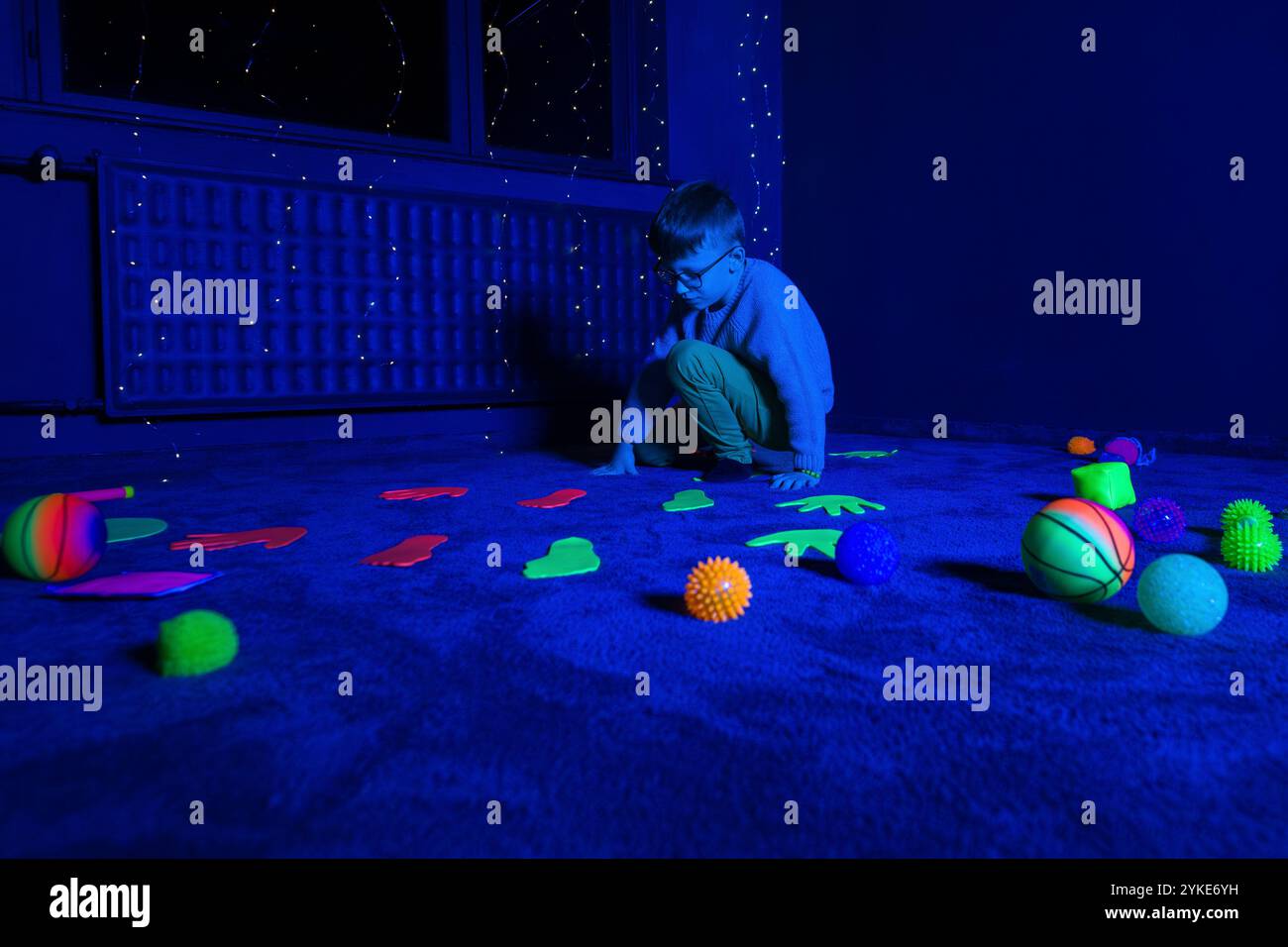 Enfant dans la salle stimulante sensorielle de thérapie, snoezelen noir. Enfant autiste jouant pendant une séance thérapeutique. Ergothérapie. Stimu sensoriel thérapeutique Banque D'Images