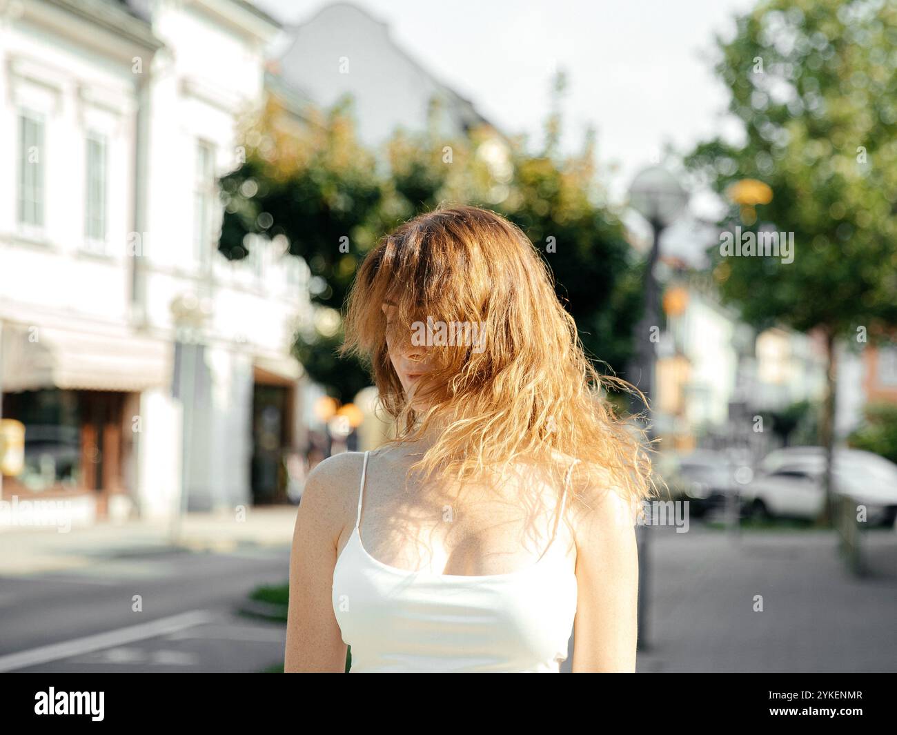 Femme debout à l'extérieur avec des cheveux soufflant le vent sur une journée ensoleillée brillante Banque D'Images