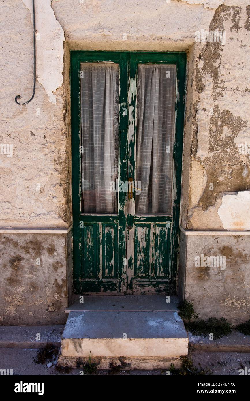 Vieux bois vert et porte en verre avec rideaux bleus et blancs dans l'île de Favignana à Trapani Sicile Italie Banque D'Images