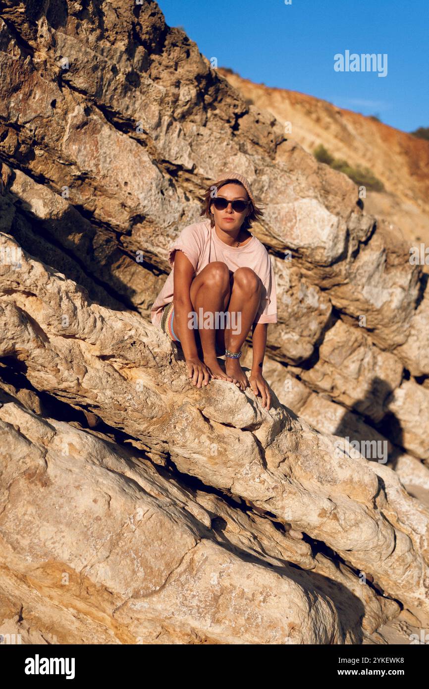 Jeune femme sur la plage dans l'Algarve assis sur le bord sur un rocher Banque D'Images