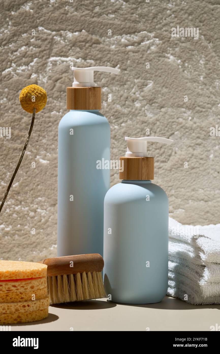 Élégantes bouteilles cosmétiques bleues associées à des bouchons en bois naturel, une fleur sèche et des essentiels de spa sur un fond texturé Banque D'Images