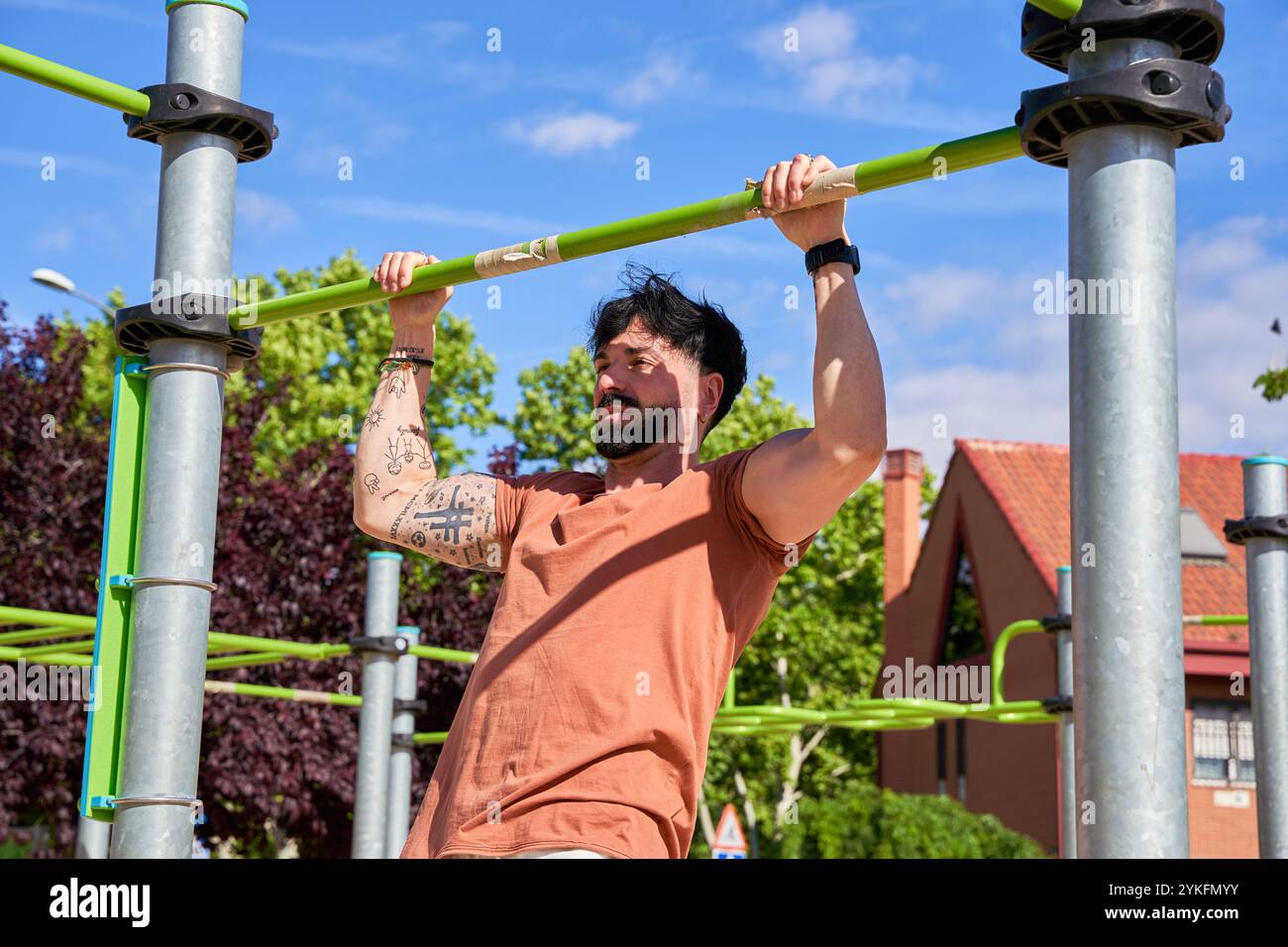 Un jeune athlète effectue des tractions dans un parc de calisthenics en plein air, faisant preuve de force et de dévouement dans un cadre d'entraînement naturel en plein air. Banque D'Images