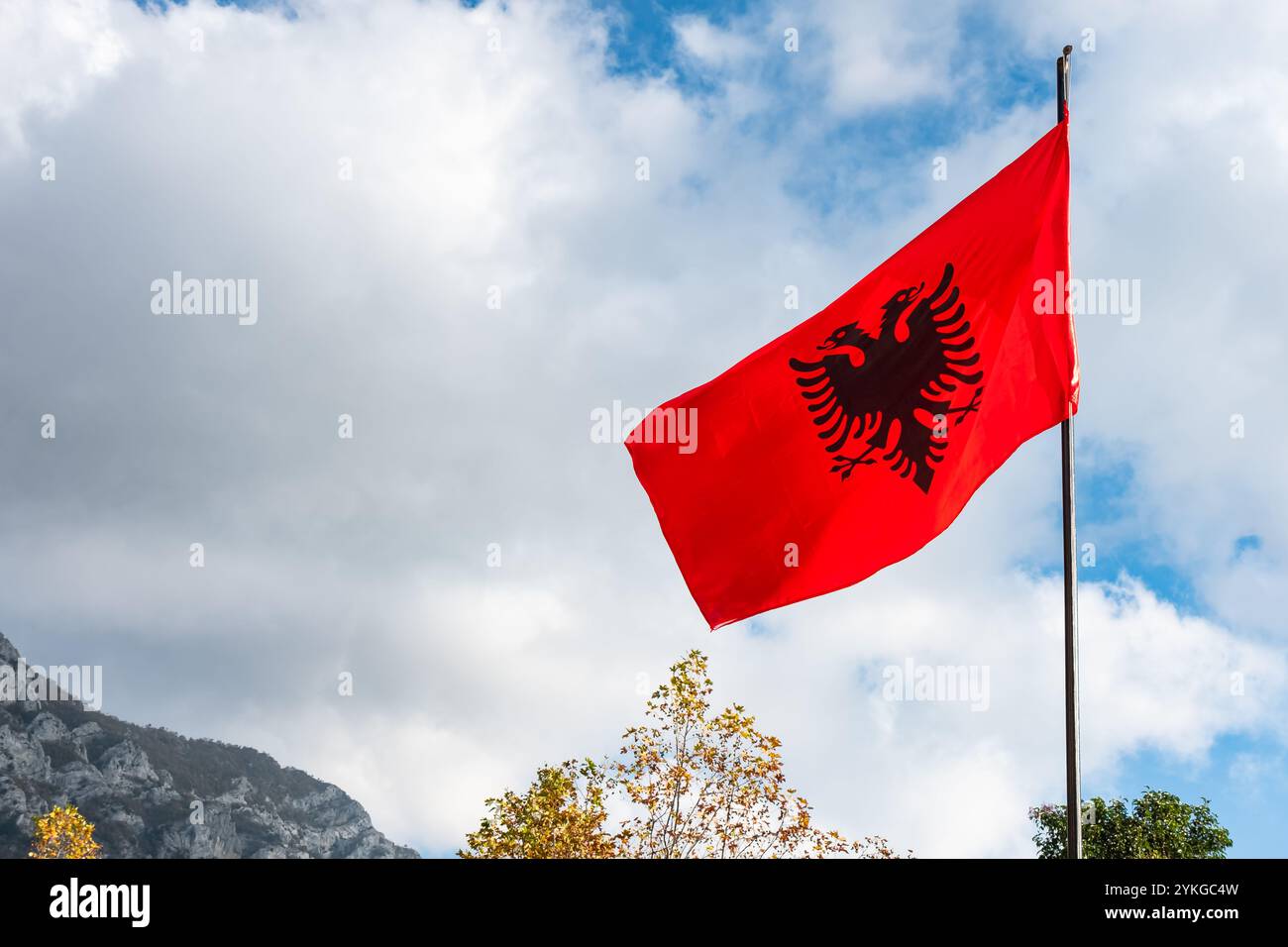 Drapeau albanais rouge avec un aigle noir à double tête flambant dans le vent sur fond de ciel bleu, rouge et noir beau drapeau albanais sur le dessus d'une mounta Banque D'Images