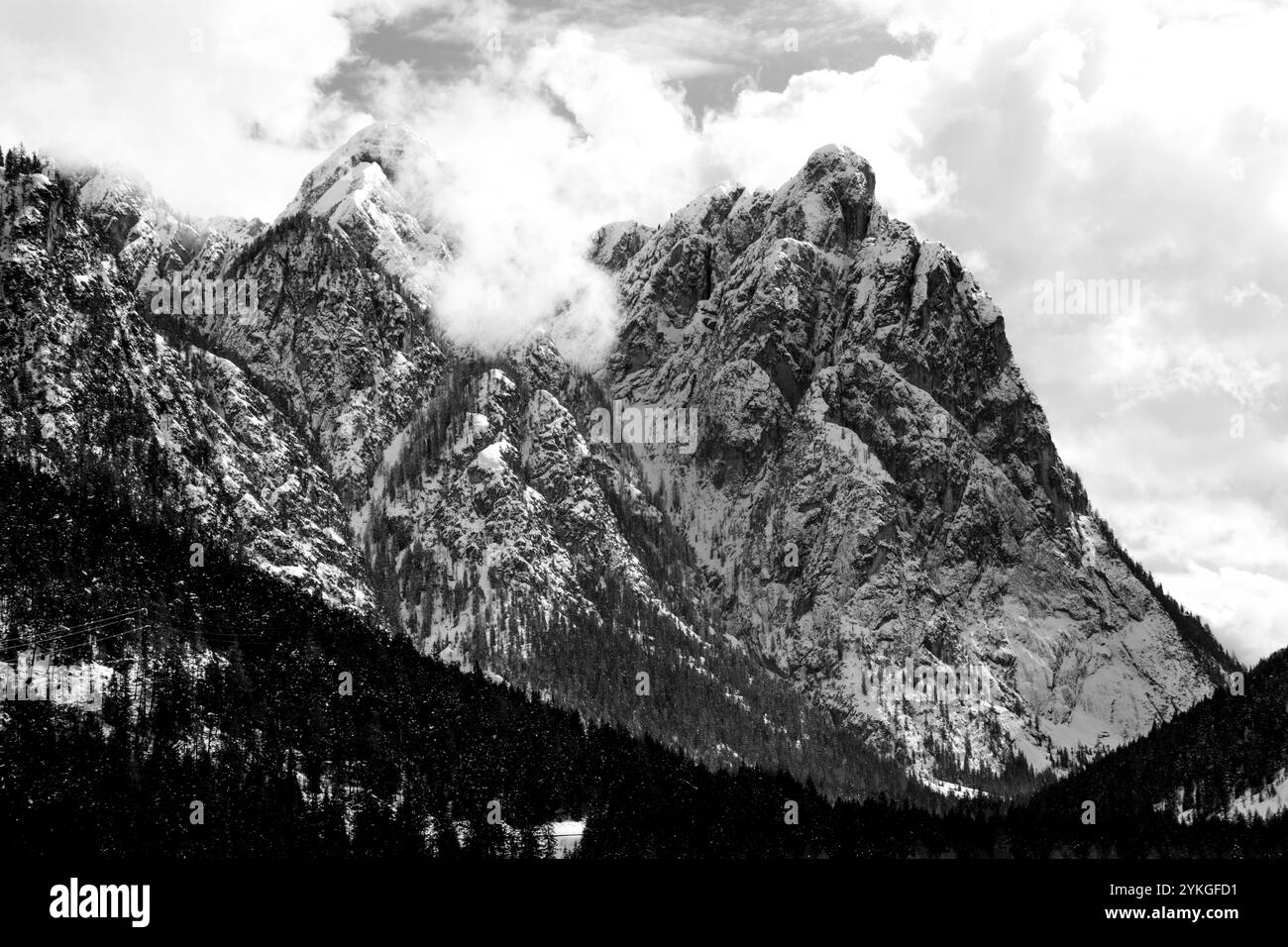 Sommets enneigés des dolomites avec des nuages et des pins autour du lac de Dobbiaco dans les Dolomites, Italie Banque D'Images