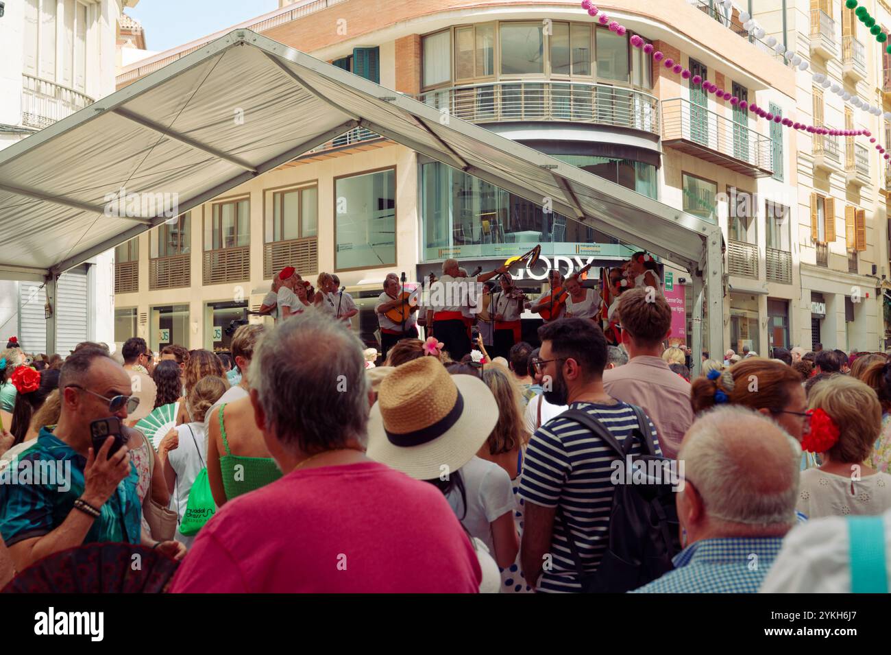 Une foule animée profite de spectacles de musique traditionnelle sous un auvent festif pendant la foire Málaga août Banque D'Images