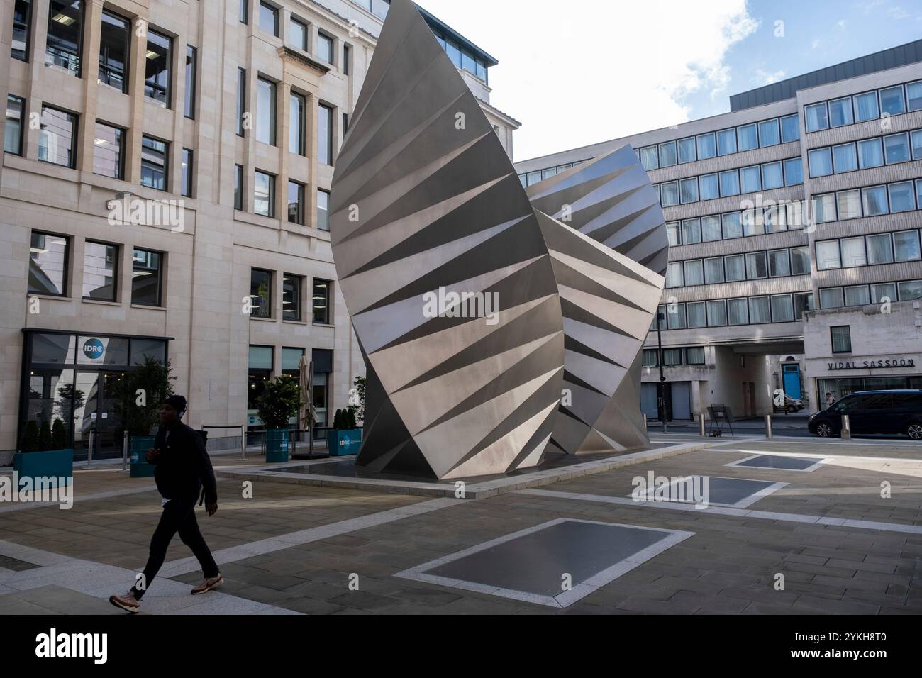 Les gens passent devant Paternoster vents, une grande sculpture publique à Paternoster Square dans la ville de Londres le 8 octobre 2024 à Londres, Royaume-Uni. Paternoster vents, également connu sous le nom de Angels Wings par l'artiste Thomas Heatherwick est une sculpture en acier inoxydable de 2002, installée sur Paternoster Lane. La sculpture assure la ventilation d'une sous-station électrique souterraine. Banque D'Images